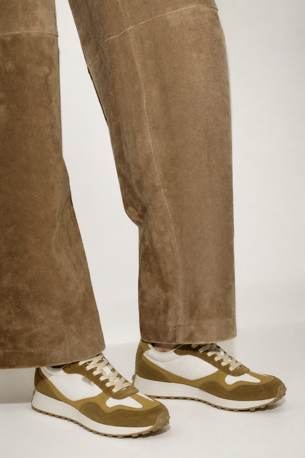 Detalle de zapatillas unisex Kuse marrones combinados con jeans doblados, estilo casual urbano moderno