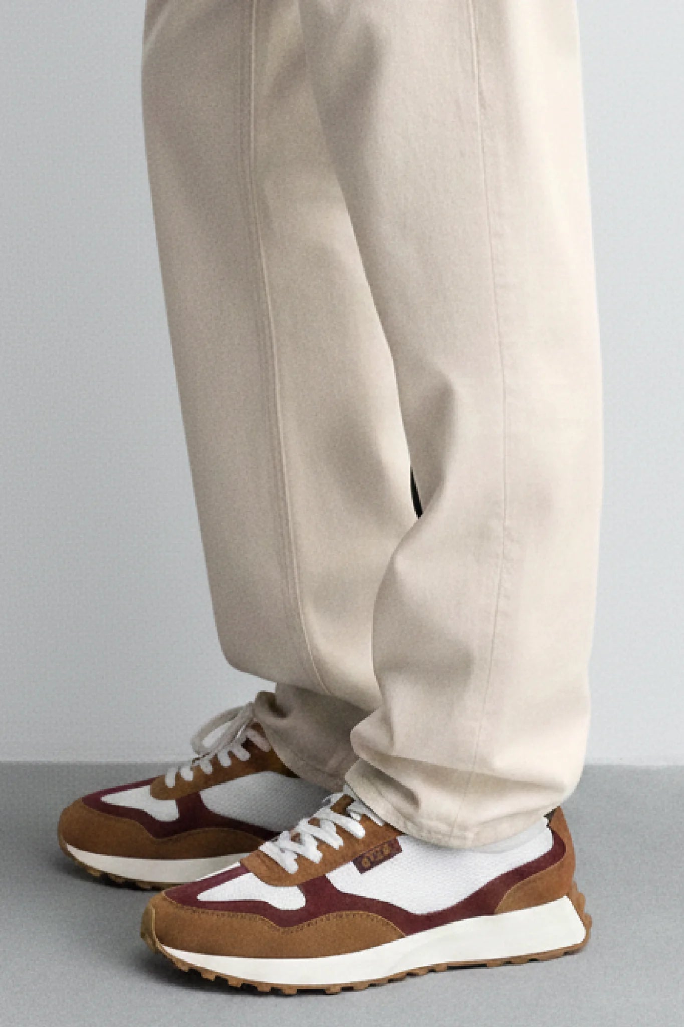 Zapatillas Kuse unisex marrón y burdeos combinadas con pantalón beige, estilo casual elegante para hombre