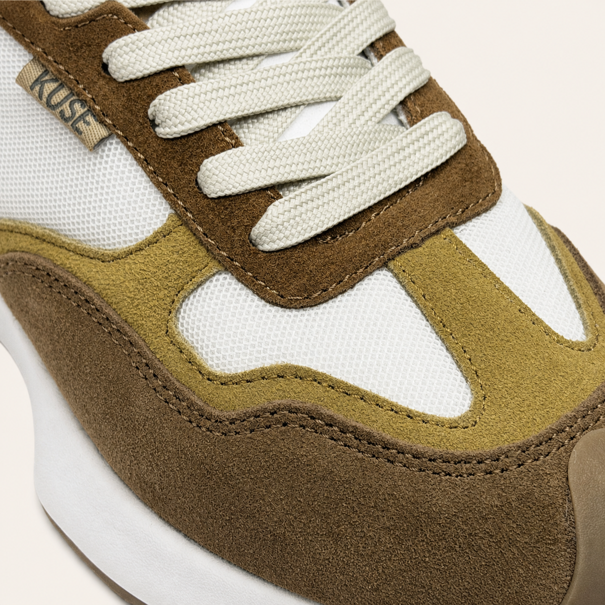 Vista detalle zapatillas casual unisex Kuse marrones combinados con cordones blancos y paneles de malla