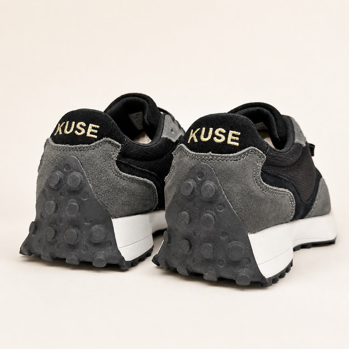 Vista trasera zapatillas casual unisex Kuse negras con logo dorado y suela de goma con tacos