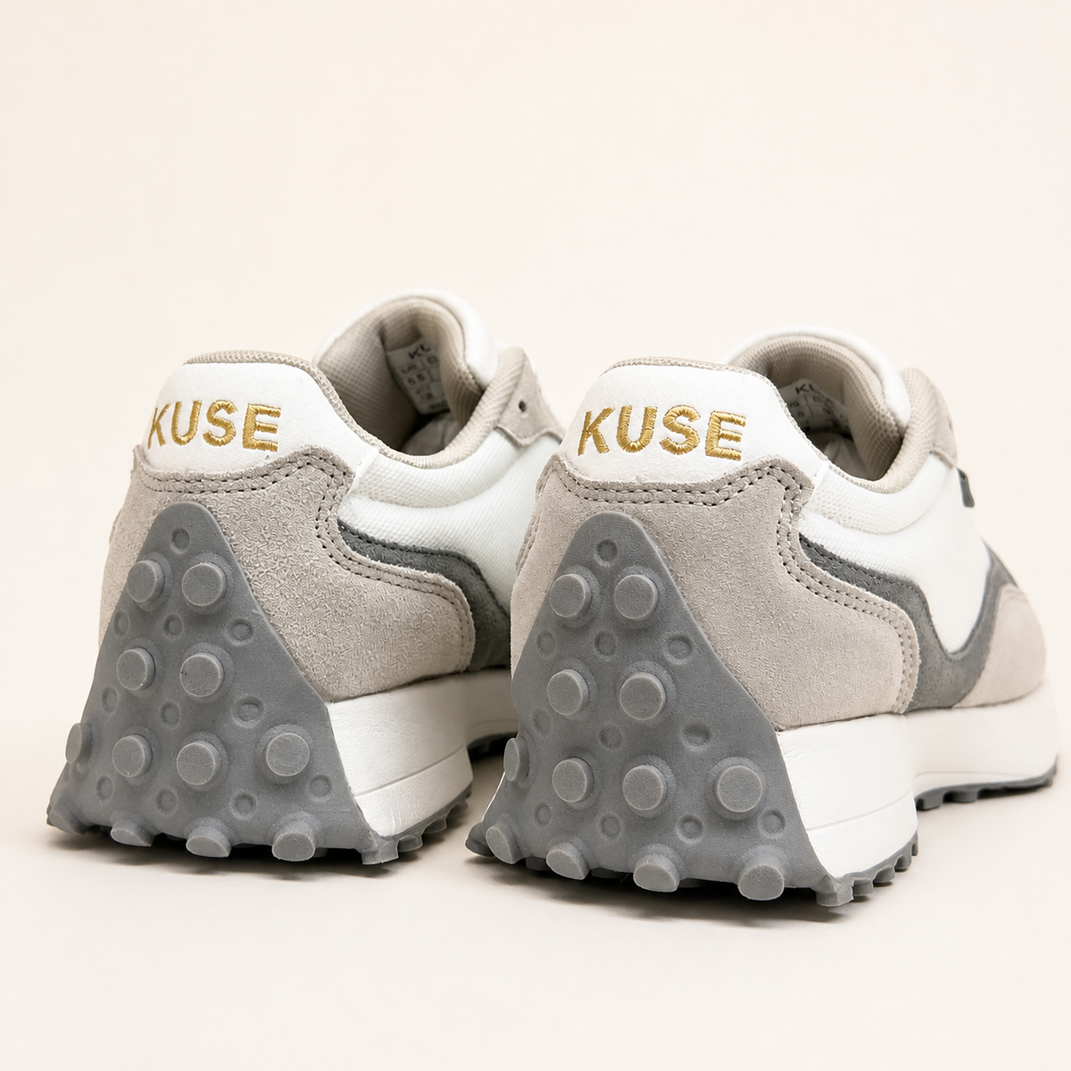 Vista trasera zapatillas Kuse beige y gris con logo dorado y suela de goma con tacos