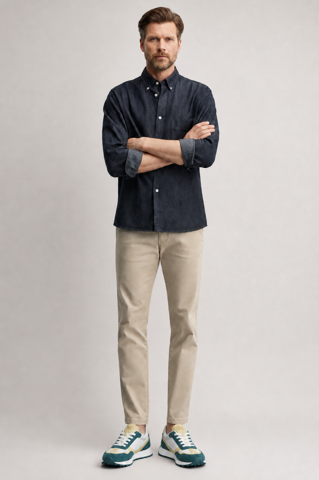 Modelo masculino con camisa denim oscura y pantalón beige usando zapatillas deportivas KUSE verde petróleo y crema.