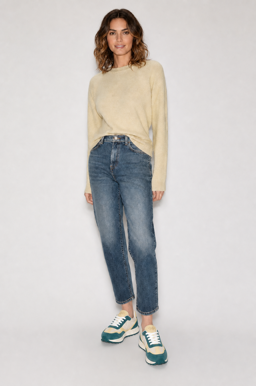 Modelo femenina con jersey beige y jeans azules usando zapatillas deportivas KUSE verde malaquita y crema