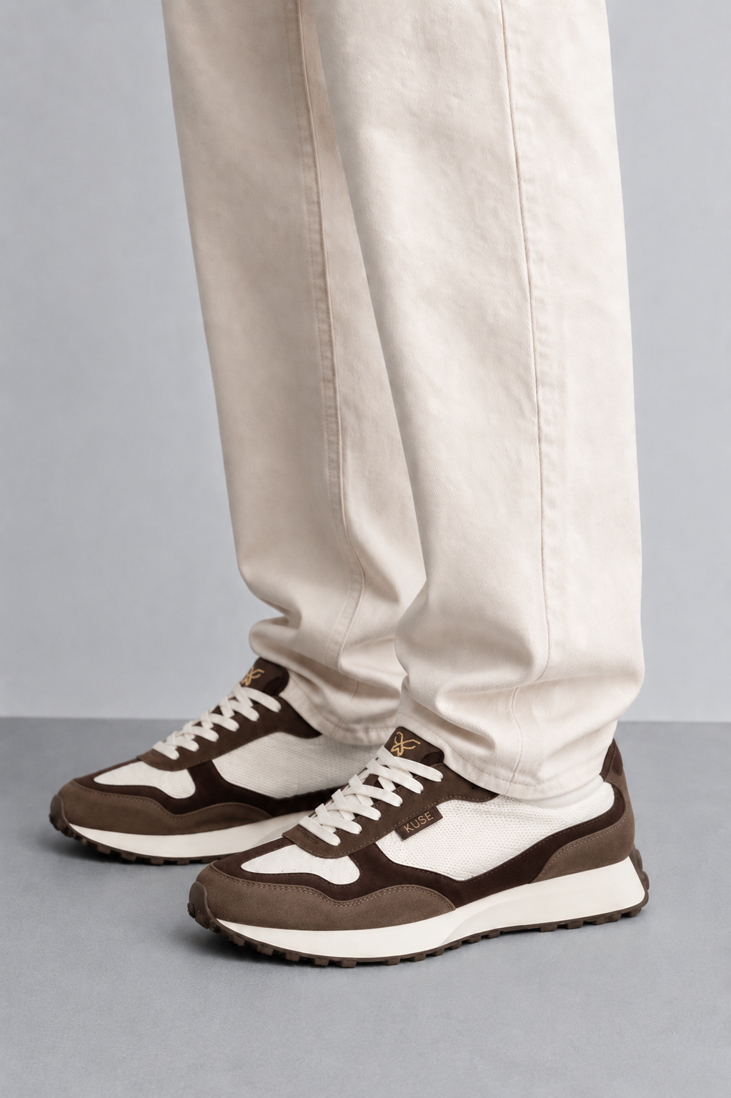 Detalle de zapatillas casual unisex marrón y burdeos con pantalón beige