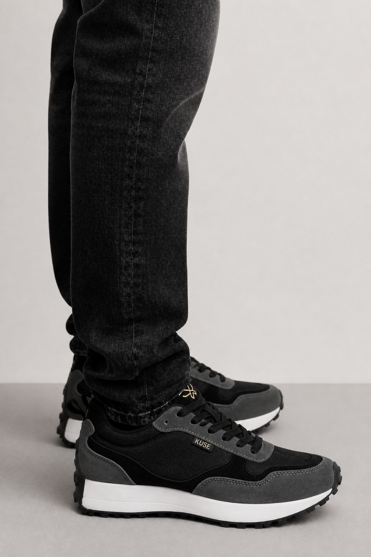 Detalle zapatillas Kuse negras unisex con jeans oscuros y suela blanca de contraste
