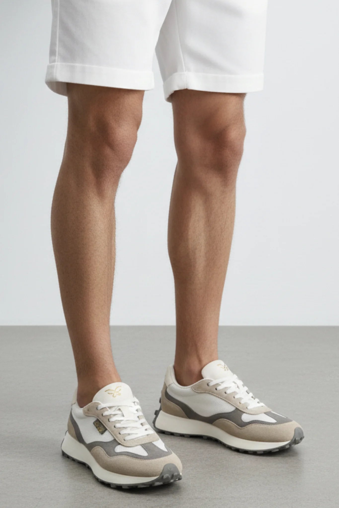 Detalle zapatillas Kuse unisex beige gris con bermudas blancas y suela dentada gris