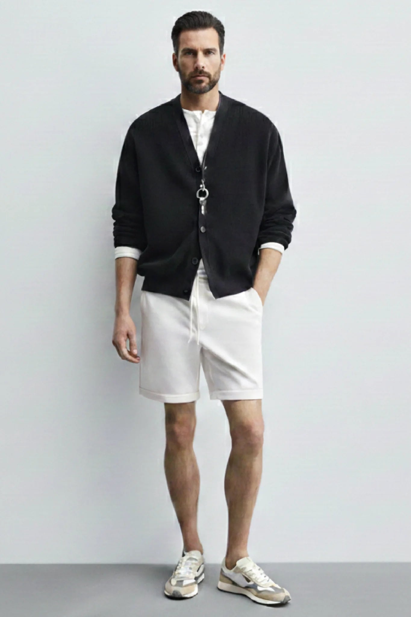 Look masculino con zapatillas casual Kuse beige y gris combinadas con bermudas blancas y chaqueta negra