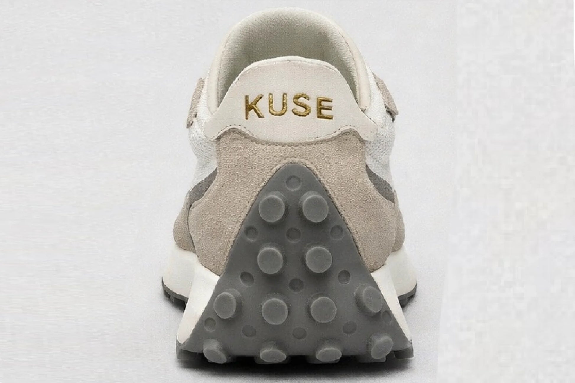 Vista trasera zapatillas Kuse beige y gris con logo dorado y suela de goma con tacos
