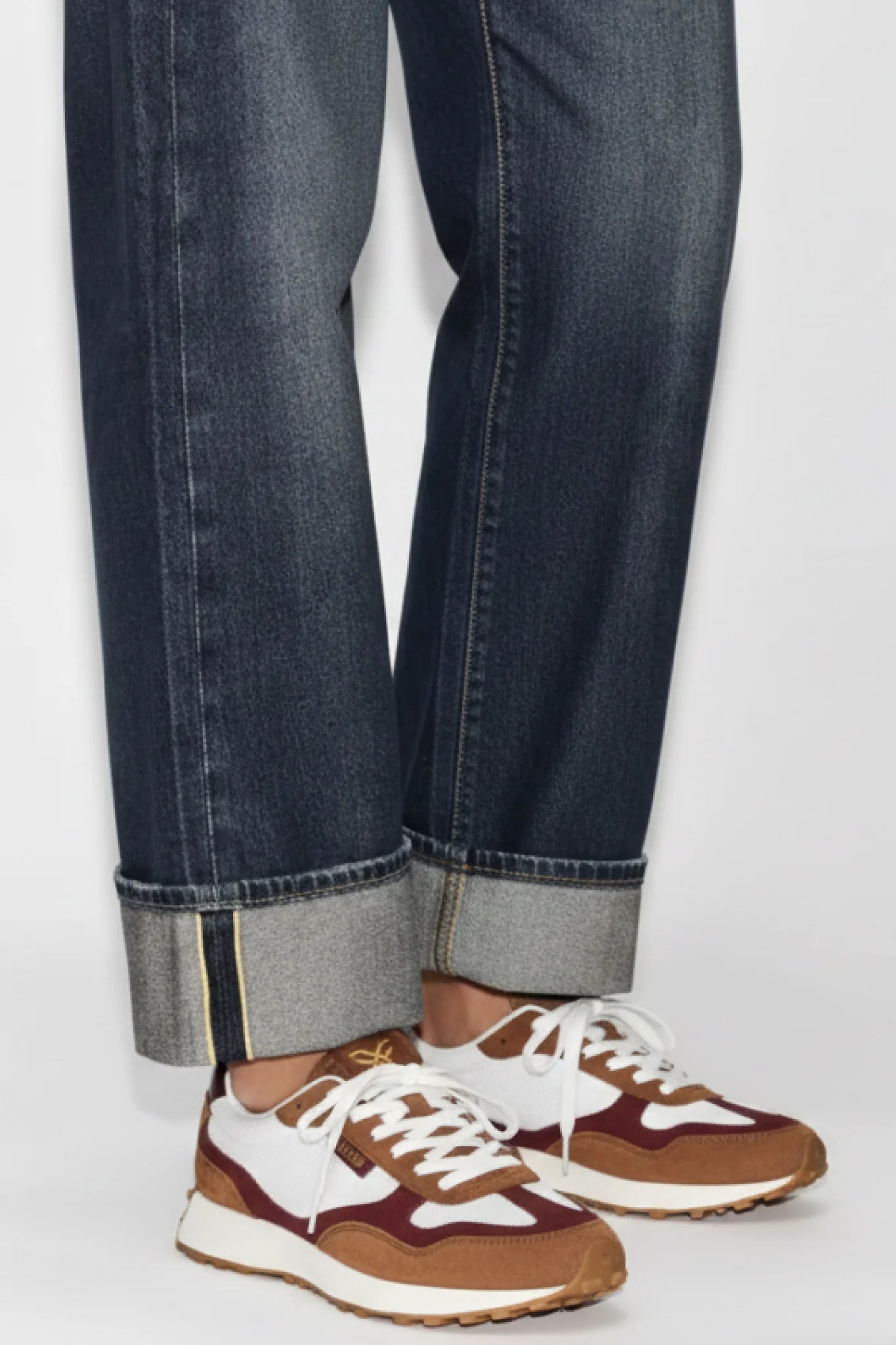 Detalle de zapatillas unisex Kuse marrón y burdeos con jeans doblados, estilo casual urbano moderno