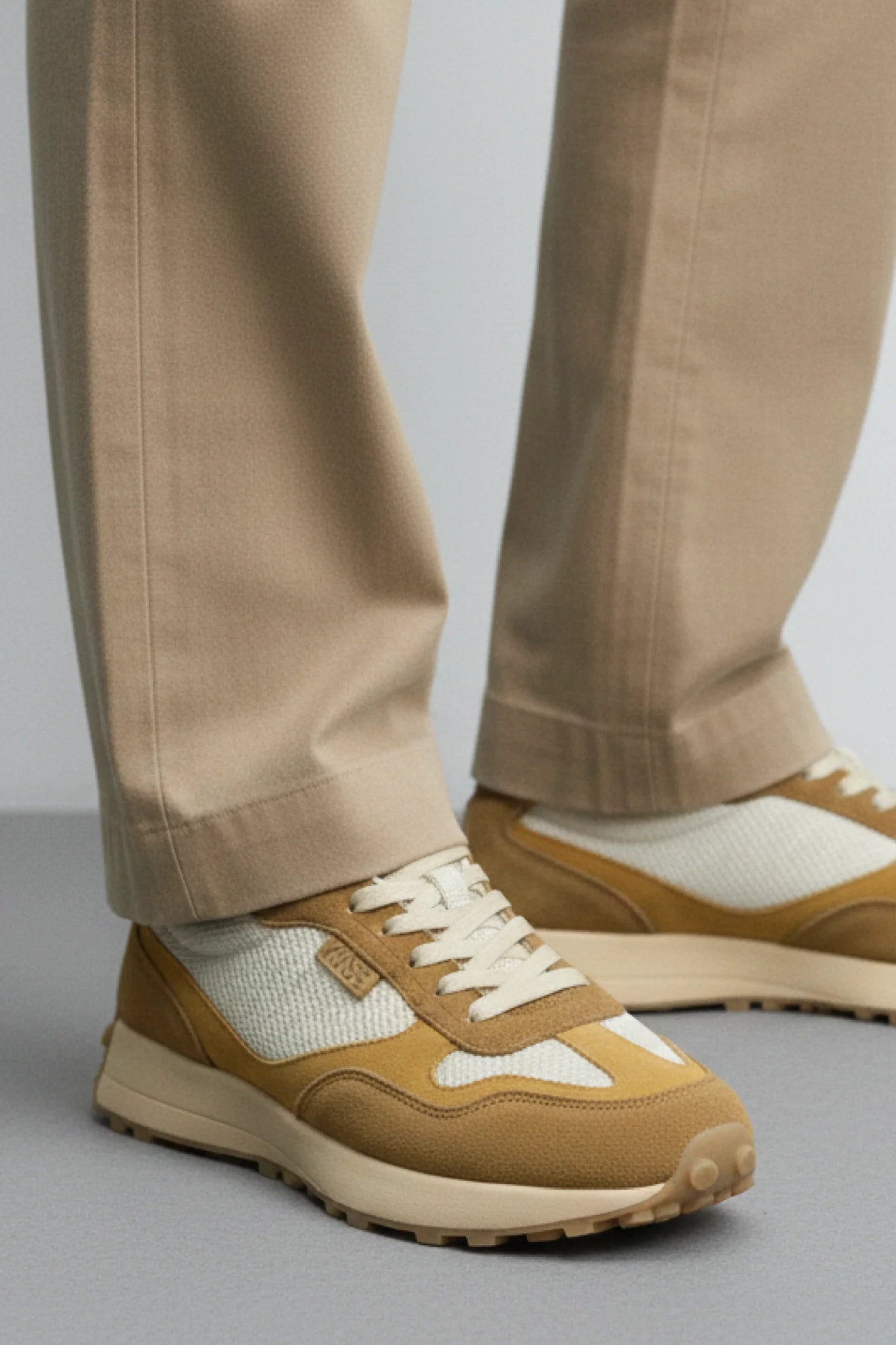 Zapatillas Kuse unisex marrones combinadas con pantalón beige, estilo casual elegante para hombre