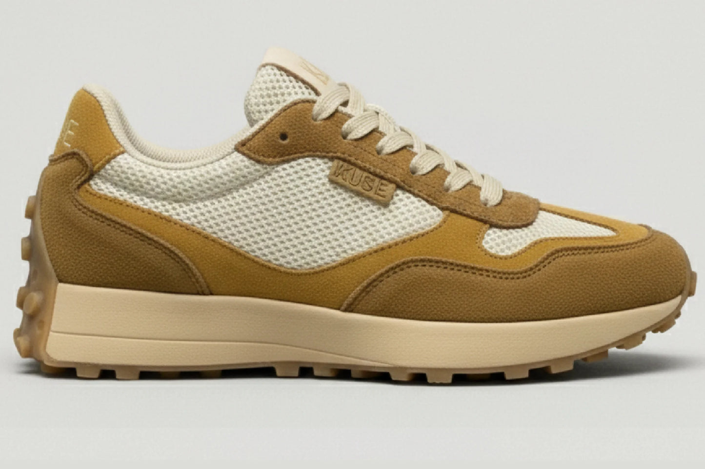 Zapatillas casual unisex Kuse tones marrones vista lateral con diseño retro, malla blanca y suela dentada beige