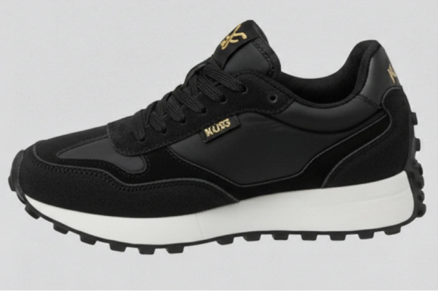 Perfil lateral izquierdo zapatillas casual unisex Kuse negras con suela gruesa blanca y detalle dorado