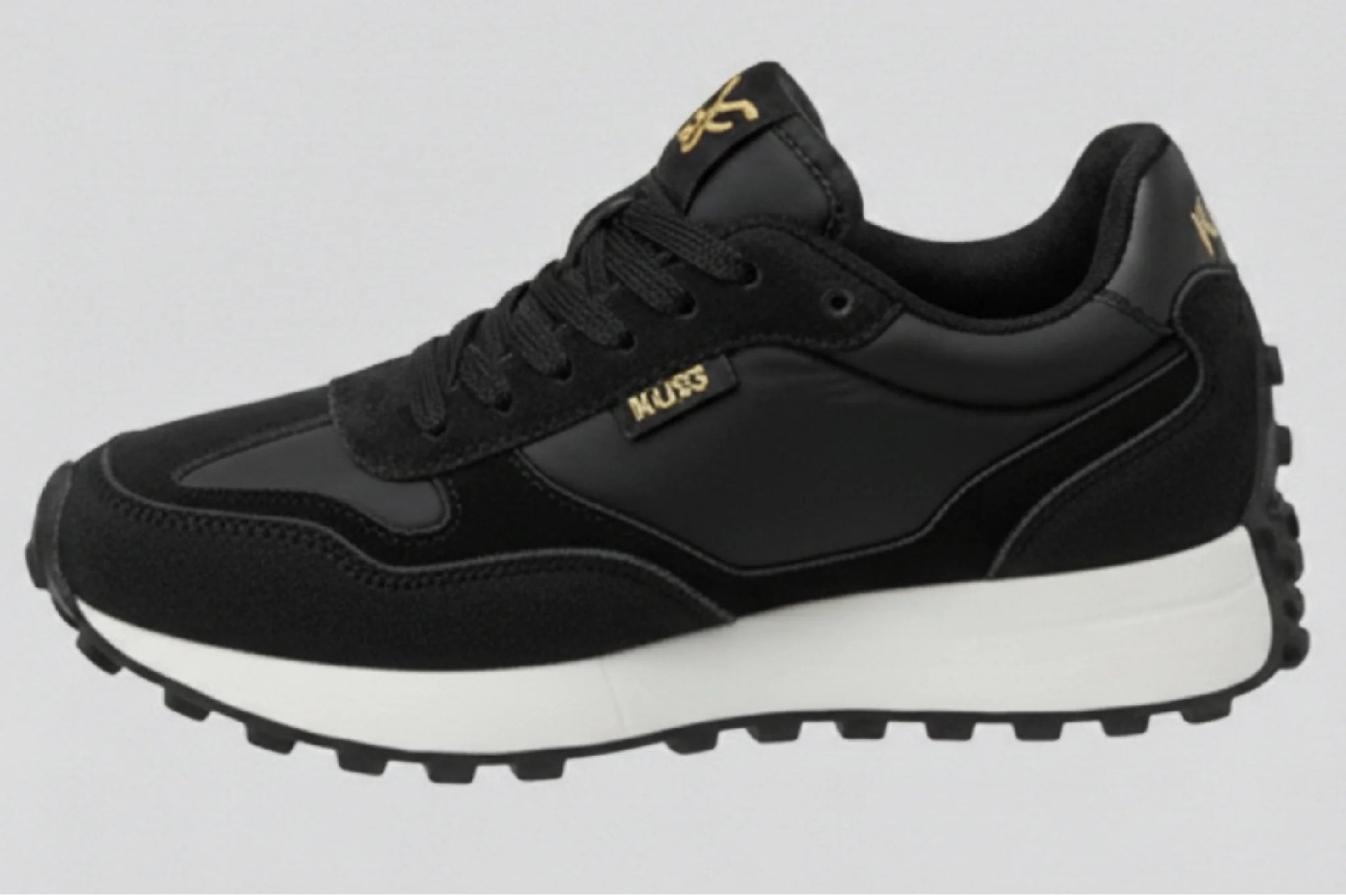 Perfil lateral izquierdo zapatillas casual unisex Kuse negras con suela gruesa blanca y detalle dorado