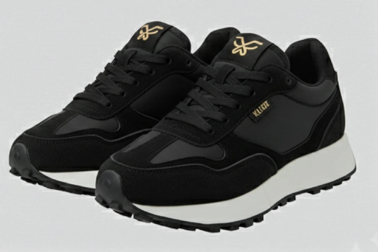 Vista tres cuartos par zapatillas Kuse negras con logo dorado y diseño retro contemporáneo