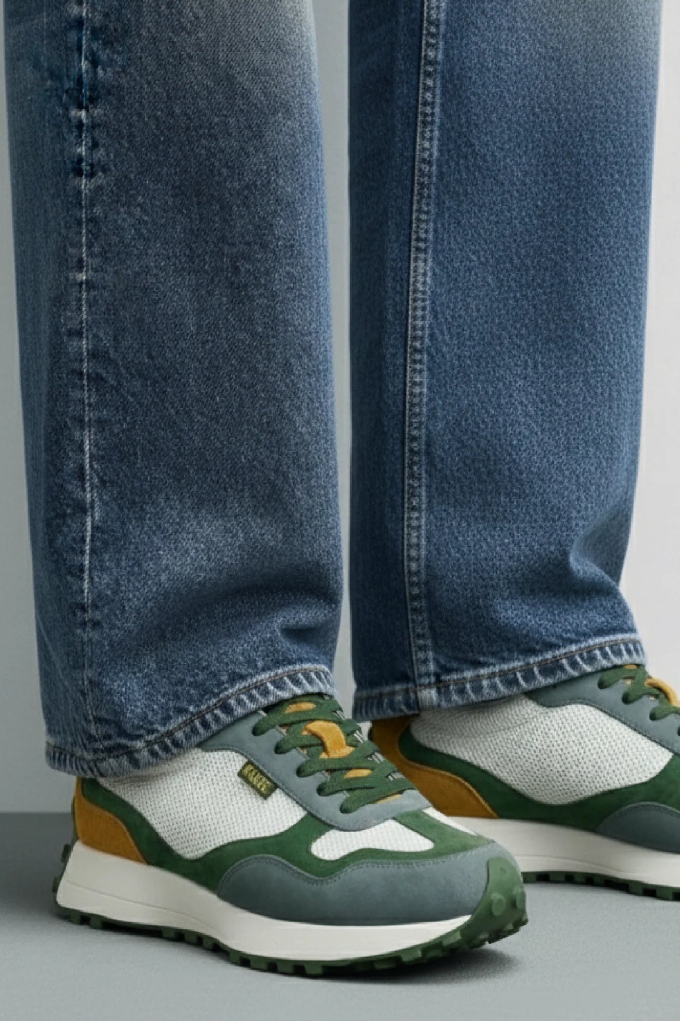 Detalle zapatillas casual unisex Kuse verde azul mostaza bajo jeans rectos estilo urbano contemporáneo