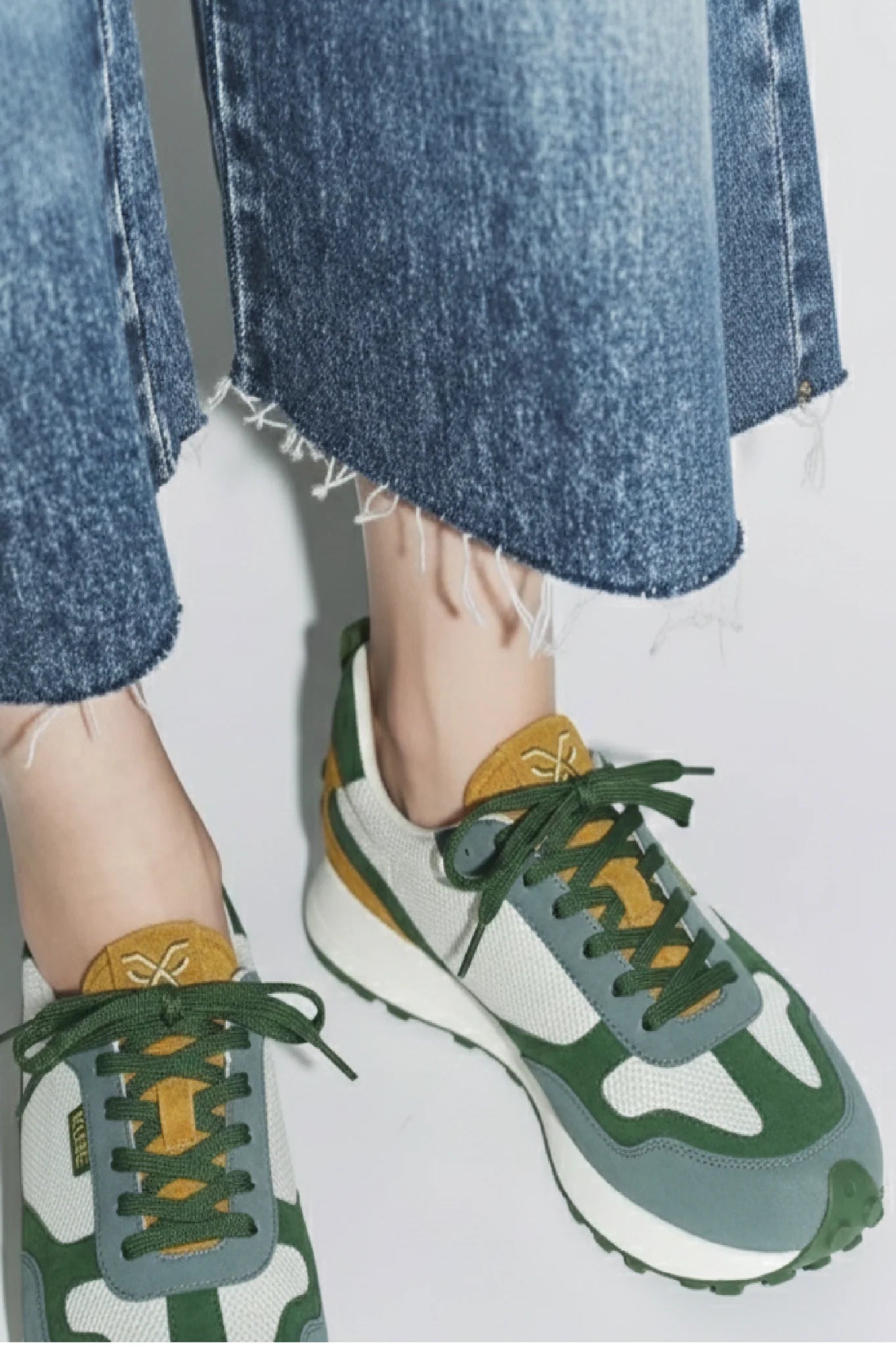 Detalle outfit femenino con zapatillas Kuse verde azul mostaza y acabado en ante y malla blanca